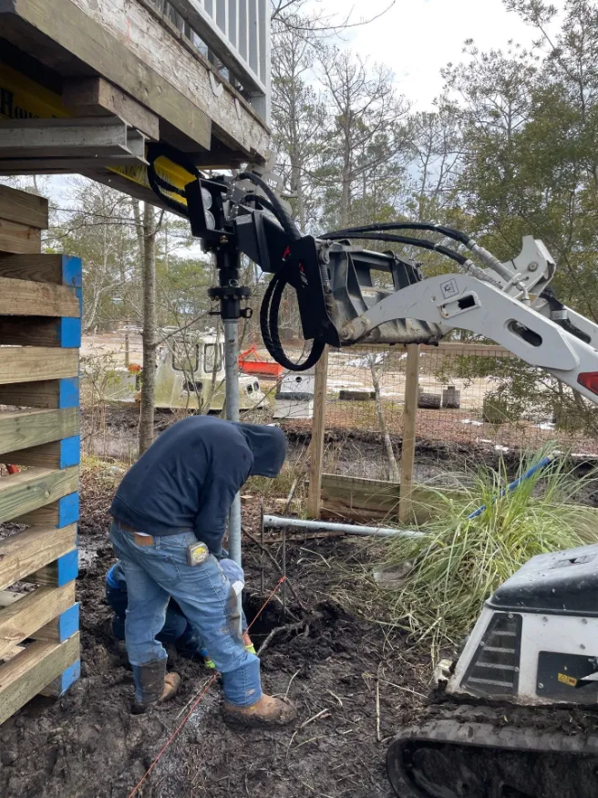Helical piers being installed under a residential property (project 2)